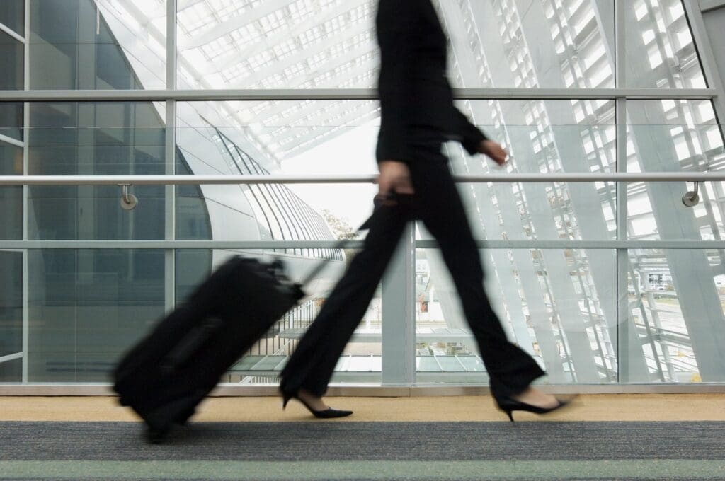 A woman walking with her luggage in the air.