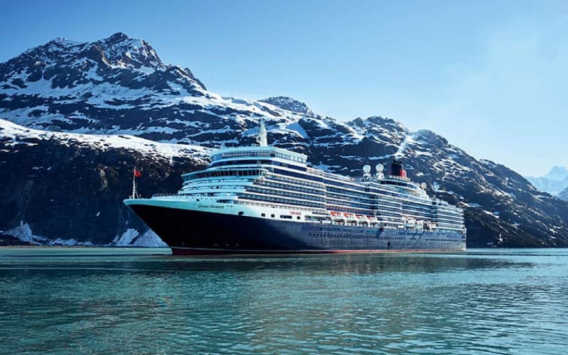 Cruise ship in front of snowy mountains.