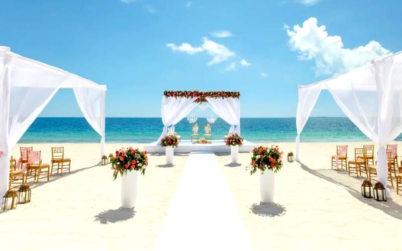 Beach wedding ceremony with white drapes.