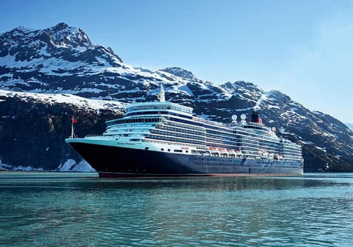 Cruise ship in front of snowy mountains.