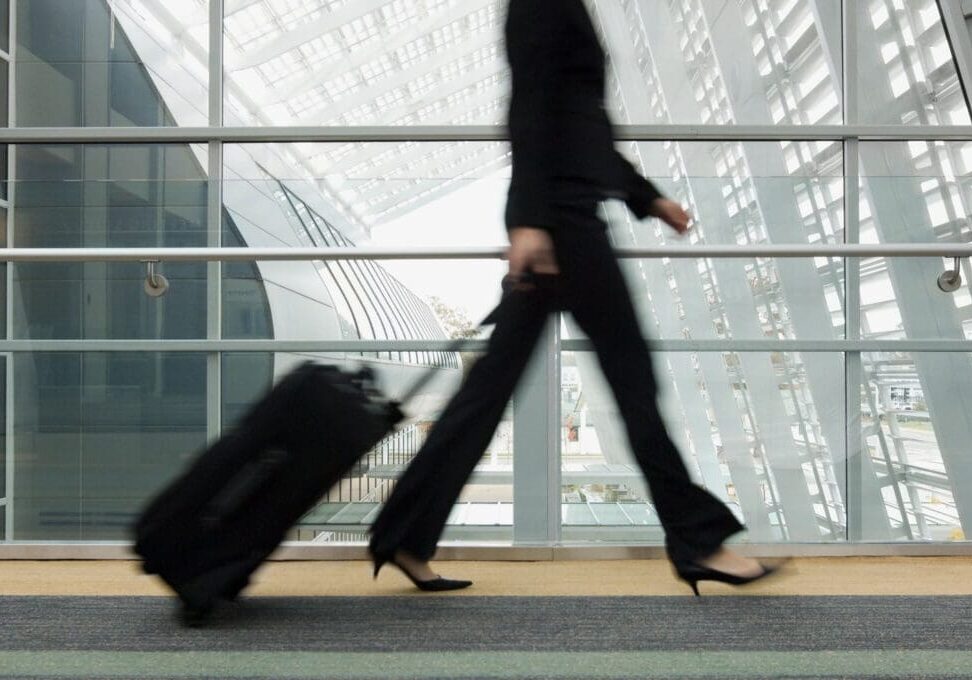 A woman walking with her luggage in the air.